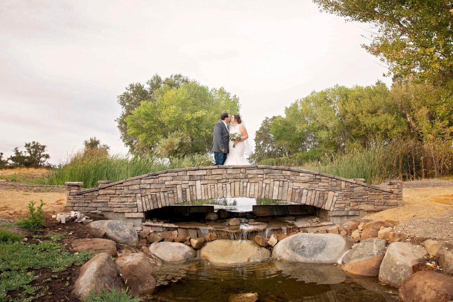 Bride and groom pose together for a photo on a bridge at Fallen Oaks Estate in Paso Robles, CA